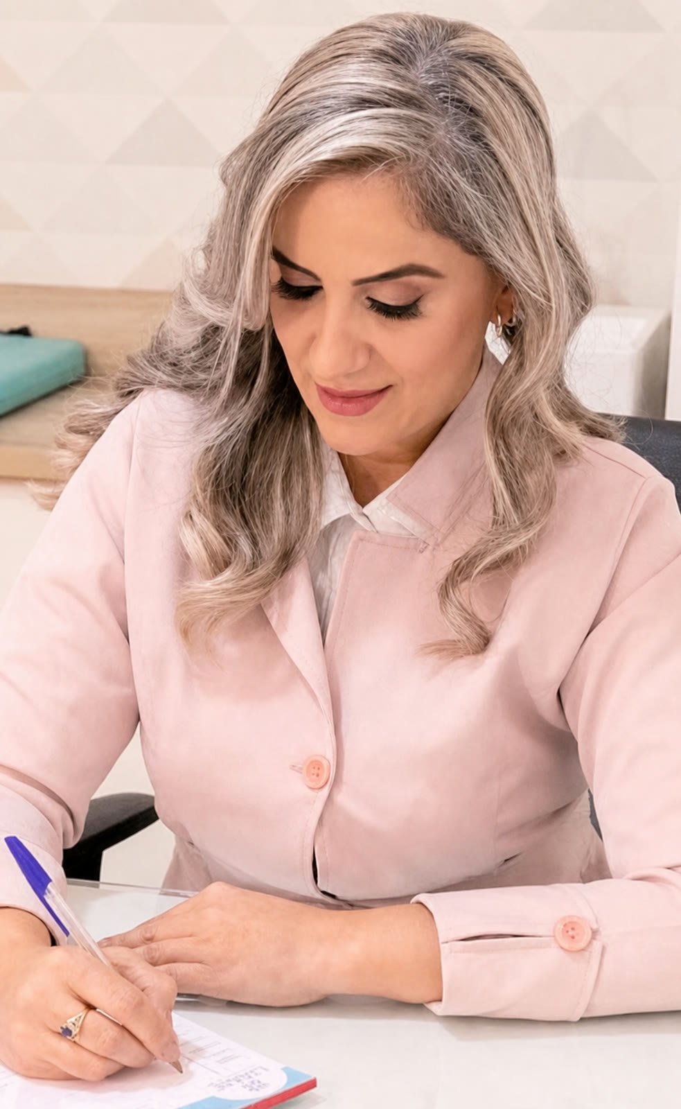 Taciana Albuquerque escrevendo em uma mesa de atendimento