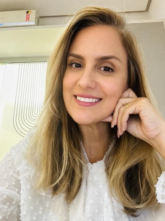 Retrato de Taciana Albuquerque apoiando o rosto na mão, com luz natural ao fundo